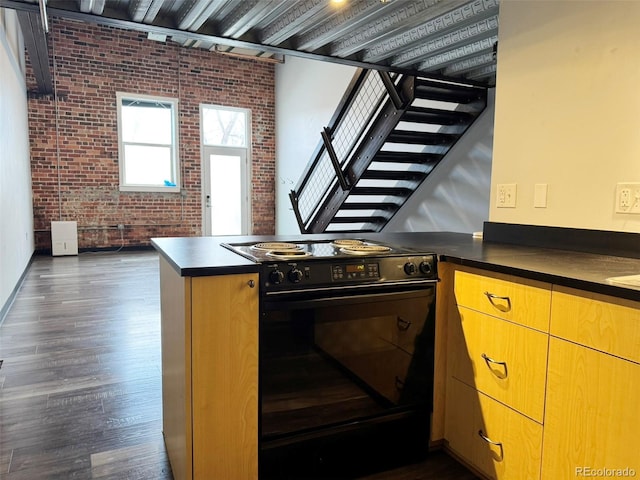 1111 Osage St Unit 7, Denver, CO 80204 - kitchen with black range with electric cooktop, brick wall, dark countertops, a peninsula, and dark wood-type flooring
