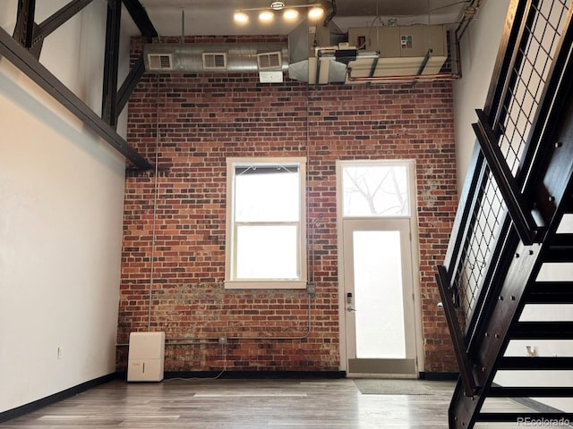 1111 Osage St Unit 7, Denver, CO 80204 - entrance foyer with brick wall, a high ceiling, wood finished floors, baseboards, and stairway