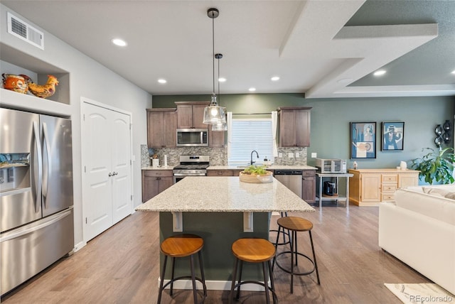 kitchen featuring pendant lighting, hardwood / wood-style flooring, stainless steel appliances, and a center island