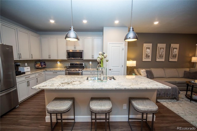 359 Courtfield Way, Castle Pines, CO 80108 - kitchen featuring appliances with stainless steel finishes, a sink, a breakfast bar, open floor plan, and recessed lighting