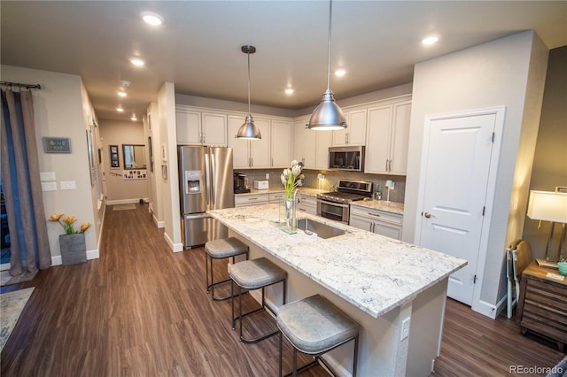 359 Courtfield Way, Castle Pines, CO 80108 - kitchen featuring appliances with stainless steel finishes, a sink, a breakfast bar area, baseboards, and dark wood finished floors