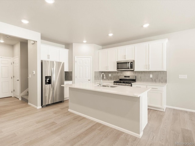 kitchen featuring stainless steel appliances, a kitchen island with sink, sink, and white cabinets