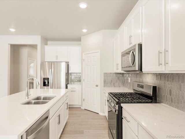 kitchen featuring sink, light hardwood / wood-style flooring, white cabinetry, backsplash, and stainless steel appliances