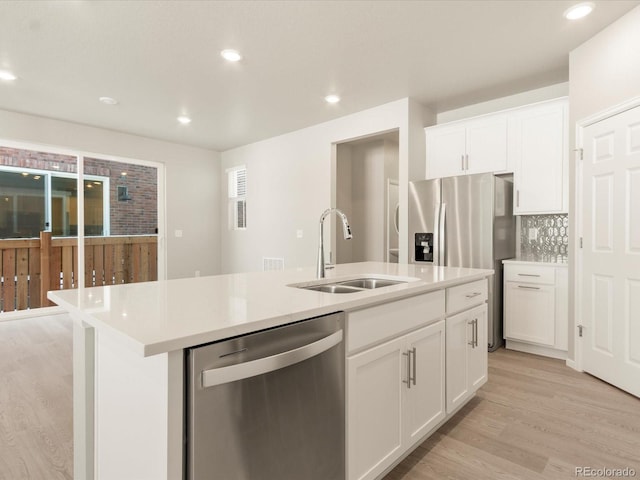 kitchen with sink, a kitchen island with sink, white cabinetry, stainless steel appliances, and light hardwood / wood-style floors