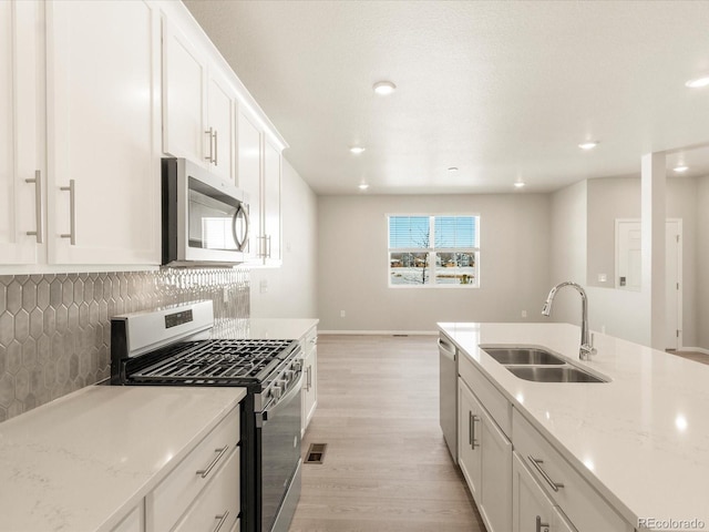 kitchen with light stone counters, sink, stainless steel appliances, and white cabinets