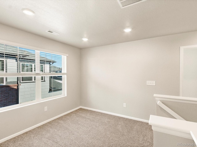 empty room with carpet flooring and a textured ceiling