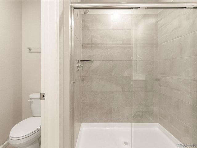 bathroom featuring toilet and a shower with shower door