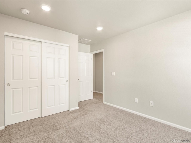 unfurnished bedroom featuring light carpet and a closet