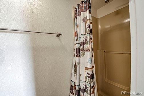 8500 Ryan Gulch Rd Unit 101, Silverthorne, CO 80498 - full bathroom featuring a textured wall and a shower with shower curtain