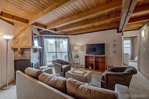 8500 Ryan Gulch Rd Unit 101, Silverthorne, CO 80498 - carpeted living area with a fireplace, healthy amount of natural light, beam ceiling, and wood ceiling