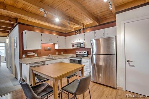 8500 Ryan Gulch Rd Unit 101, Silverthorne, CO 80498 - kitchen featuring appliances with stainless steel finishes, rail lighting, wood ceiling, beam ceiling, and light wood finished floors
