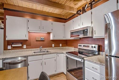 8500 Ryan Gulch Rd Unit 101, Silverthorne, CO 80498 - kitchen featuring stainless steel appliances, wooden ceiling, a sink, beamed ceiling, and light countertops