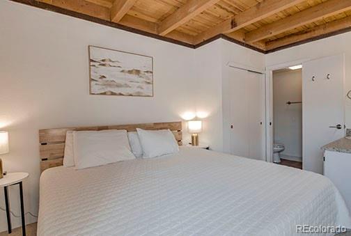 8500 Ryan Gulch Rd Unit 101, Silverthorne, CO 80498 - bedroom with wood ceiling, beamed ceiling, and connected bathroom