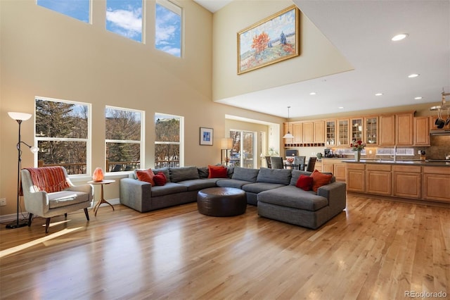 living room with a high ceiling, sink, and light wood-type flooring