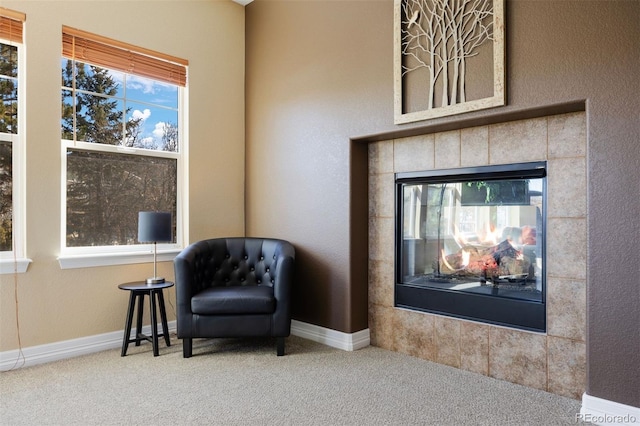 living area with a tile fireplace and carpet