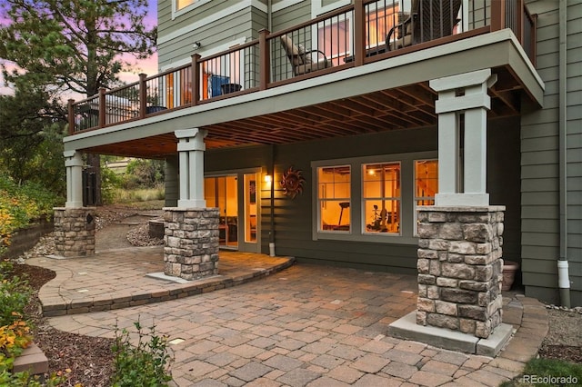 patio terrace at dusk featuring a balcony