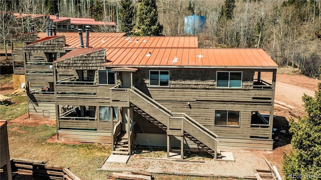 rear view of property with a standing seam roof, metal roof, and stairs