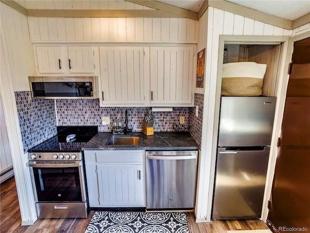 kitchen featuring tasteful backsplash, appliances with stainless steel finishes, wood finished floors, and a sink