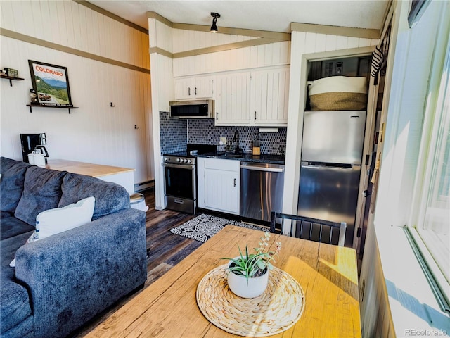 kitchen featuring dark wood-style flooring, a sink, dark countertops, white cabinetry, and stainless steel appliances