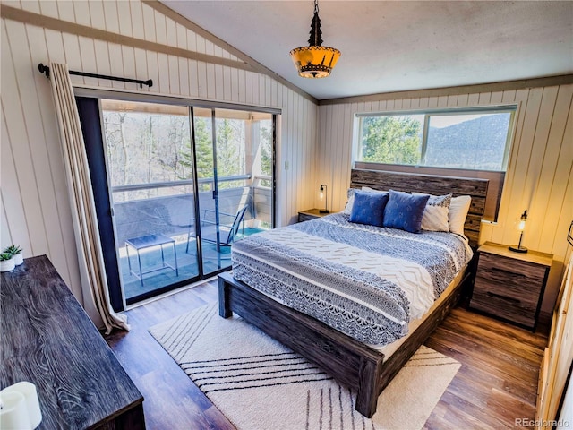 bedroom featuring access to outside, wood finished floors, wooden walls, and vaulted ceiling
