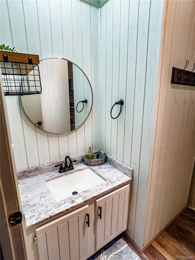 bathroom featuring wood walls, wood finished floors, and vanity