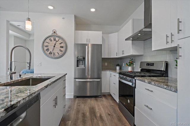 31191 Black Eagle Dr Unit 304, Evergreen, CO 80439 - kitchen featuring appliances with stainless steel finishes, wall chimney exhaust hood, a sink, wood finished floors, and white cabinets