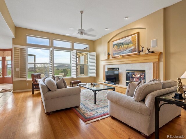 living area with a fireplace, baseboards, recessed lighting, a ceiling fan, and light wood-style flooring
