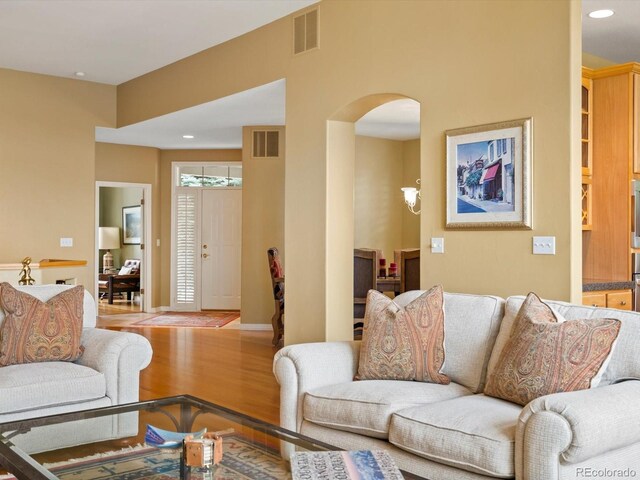 living area with arched walkways, recessed lighting, wood finished floors, and visible vents