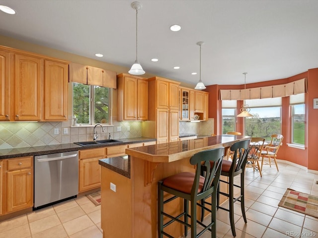 kitchen featuring a kitchen island, a kitchen bar, dishwasher, a sink, and light tile patterned flooring