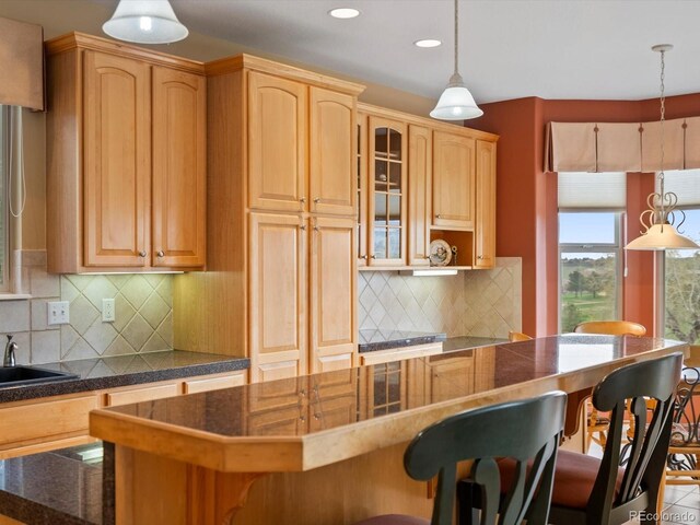 kitchen featuring a kitchen island, glass insert cabinets, a kitchen bar, recessed lighting, and tasteful backsplash