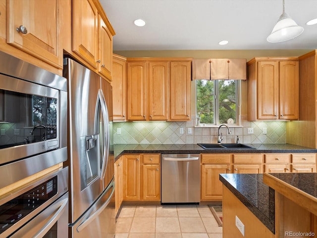 kitchen with pendant lighting, appliances with stainless steel finishes, tasteful backsplash, a sink, and light tile patterned floors