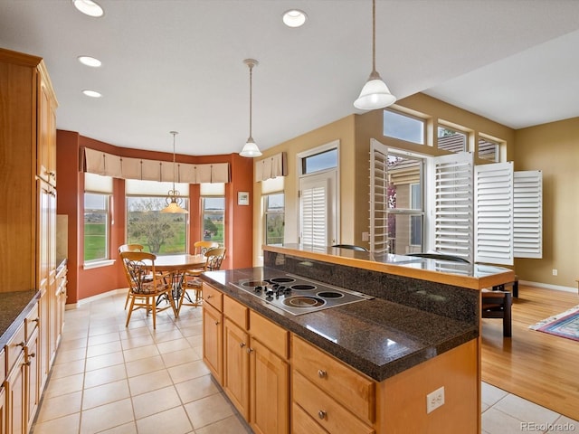 kitchen featuring light tile patterned floors, baseboards, a healthy amount of sunlight, and electric cooktop