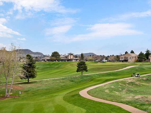 view of community with a lawn, view of golf course, and a mountain view