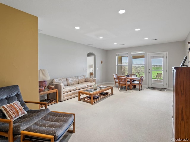 carpeted living room with arched walkways, baseboards, and recessed lighting