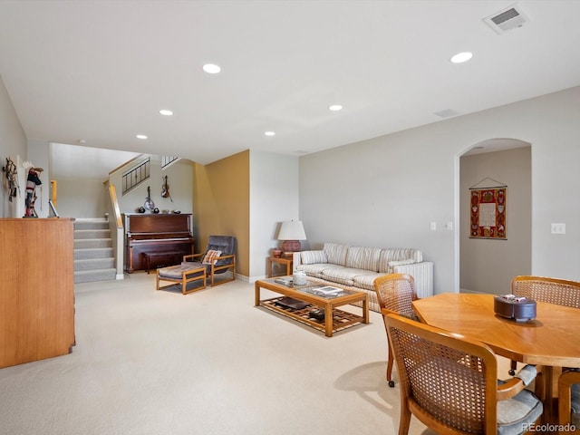 living area with visible vents, stairs, light carpet, recessed lighting, and arched walkways