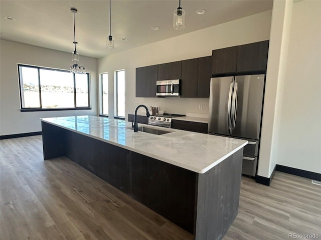 kitchen featuring sink, decorative light fixtures, light hardwood / wood-style flooring, an island with sink, and stainless steel appliances