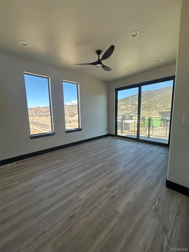 unfurnished room featuring a mountain view, dark wood-type flooring, and plenty of natural light