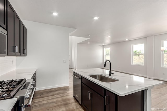 2651 E 102nd Pl, Thornton, CO 80229 - kitchen featuring appliances with stainless steel finishes, light wood-type flooring, light stone counters, recessed lighting, and a center island with sink