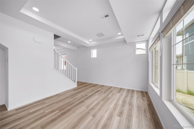 unfurnished room with visible vents, recessed lighting, light wood-type flooring, and a tray ceiling