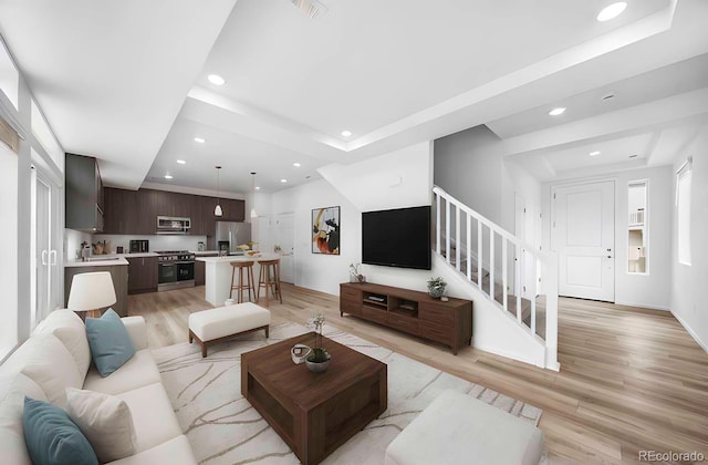 living area with light wood finished floors, visible vents, recessed lighting, and stairs