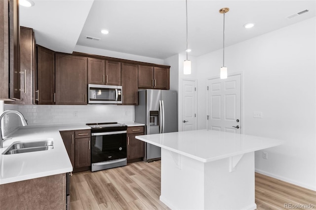 kitchen with visible vents, light wood-style flooring, a sink, tasteful backsplash, and appliances with stainless steel finishes