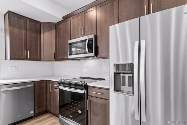 kitchen featuring tasteful backsplash, stainless steel appliances, dark brown cabinetry, light wood finished floors, and light countertops