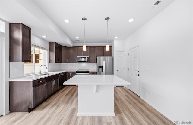 kitchen featuring a sink, tasteful backsplash, stainless steel appliances, dark brown cabinetry, and light countertops