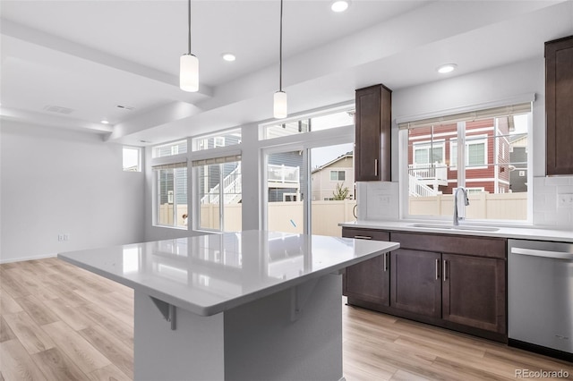 kitchen featuring a kitchen bar, light wood-type flooring, a sink, stainless steel dishwasher, and dark brown cabinetry