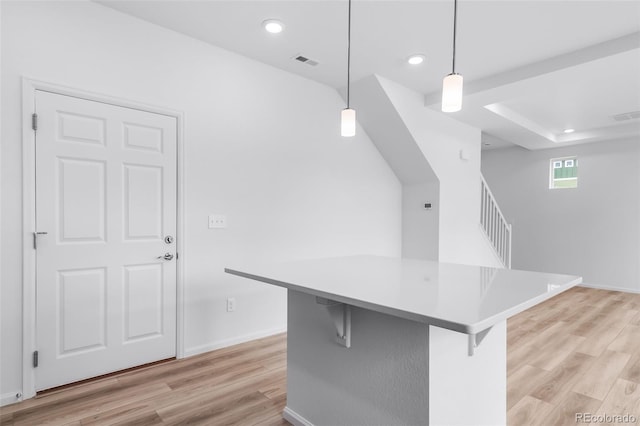 kitchen with visible vents, light wood-style flooring, recessed lighting, hanging light fixtures, and a kitchen breakfast bar