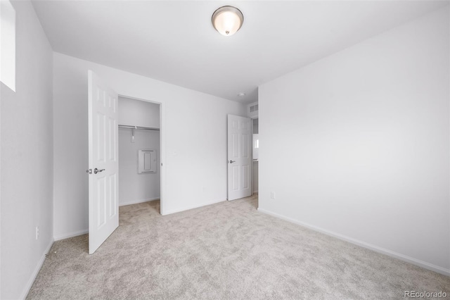 unfurnished bedroom with light carpet, a closet, and baseboards