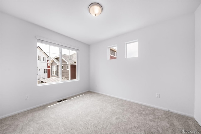 carpeted spare room featuring visible vents and baseboards