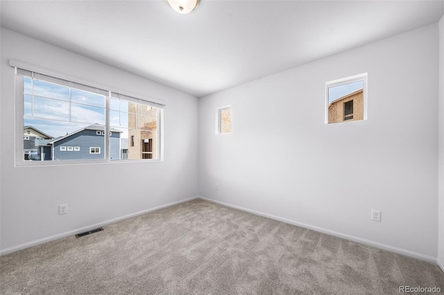 spare room featuring visible vents, baseboards, and carpet flooring