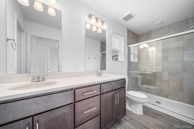 full bathroom featuring visible vents, double vanity, a sink, a shower stall, and toilet