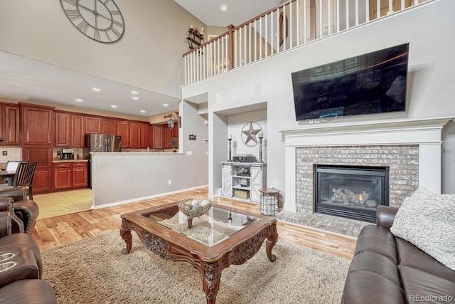 living room featuring light tile patterned floors, a towering ceiling, and a brick fireplace